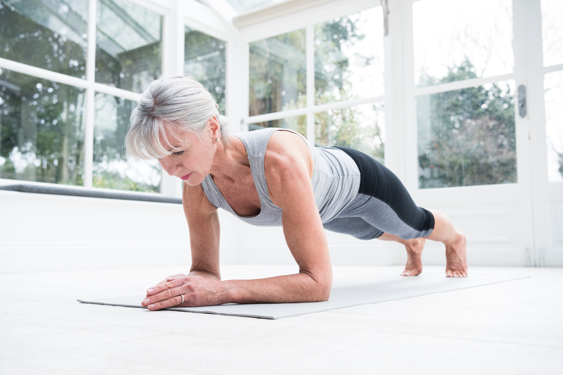 Senior woman in plank position in conservatory